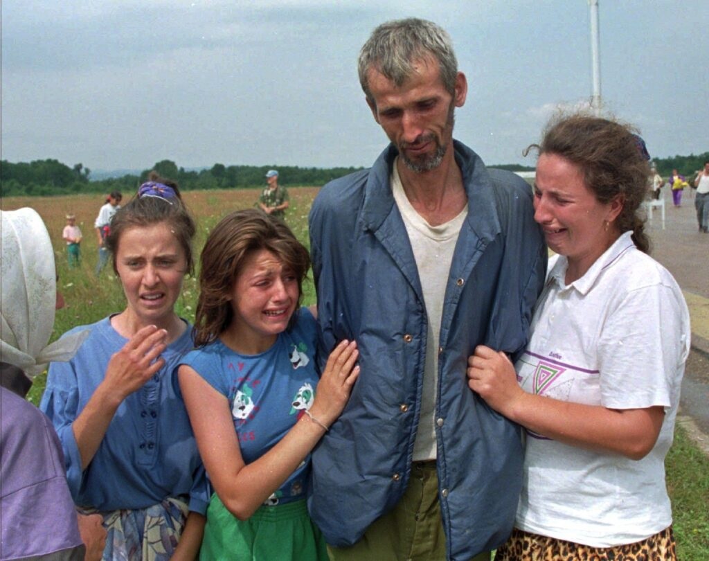 A family of Bosnian refugees cries as their father and husband arrives at the UN air base in Tuzla, Bosnia, after he survived the death march of six days from Srebrenica. (AP Photo/Michel Euler, File)
