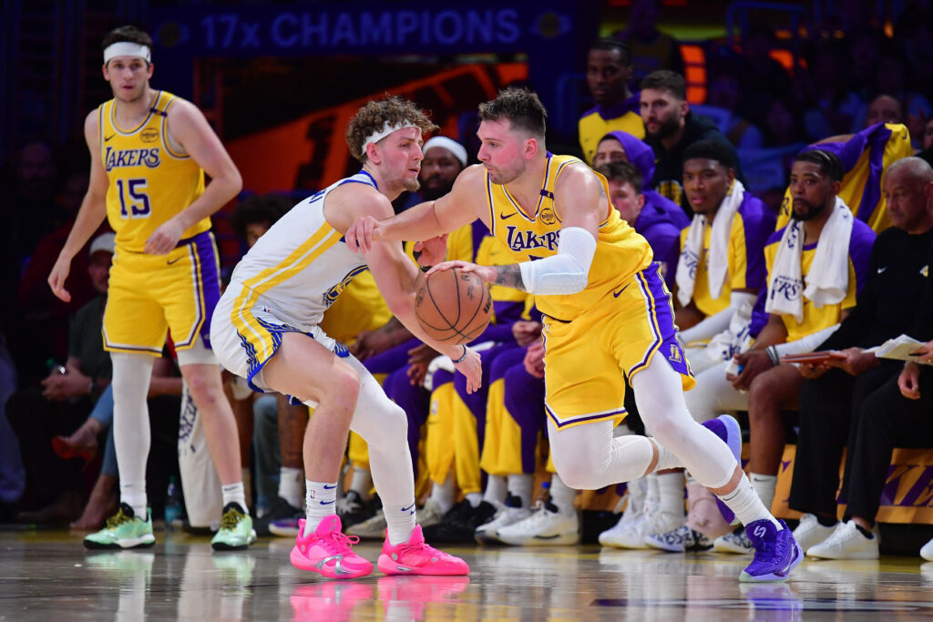 Apr 3, 2025; Los Angeles, California, USA; Los Angeles Lakers guard Luka Doncic (77) moves the ball against Golden State Warriors guard Brandin Podziemski (2) during the second half at Crypto.com Arena. Mandatory Credit: Gary A. Vasquez-Imagn Images
