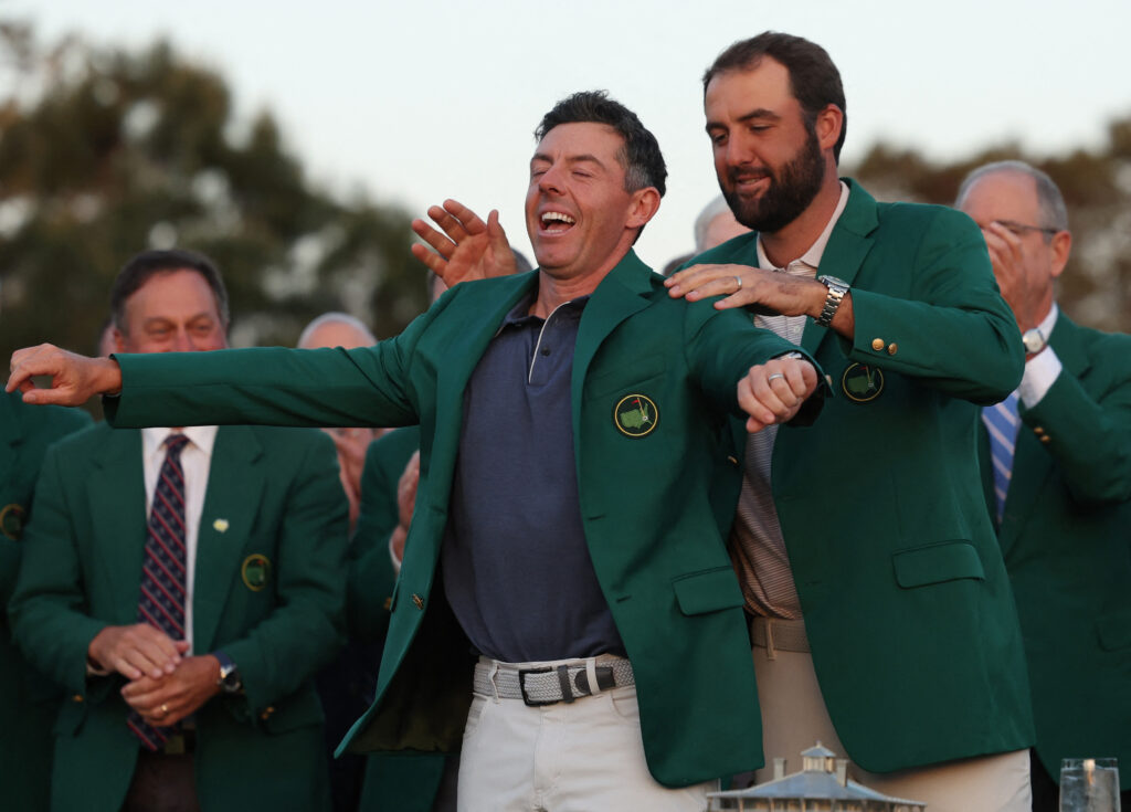 Golf - The Masters - Augusta National Golf Club, Augusta, Georgia, U.S. - April 13, 2025 Northern Ireland's Rory McIlroy is presented with the green jacket by Scottie Scheffler of the U.S. after winning The Masters and completing a career grand slam REUTERS/Pilar Olivares